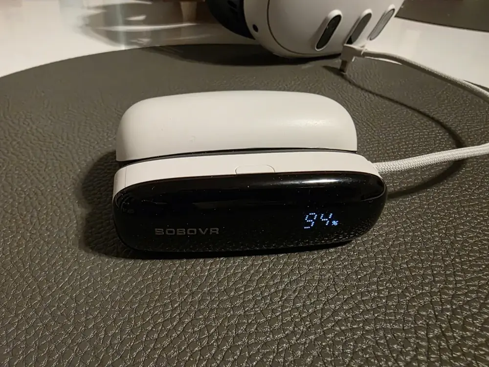 Display der BoboVR PD100 zeigt 94 Prozent Akkustand, dahinter die Meta Quest 3